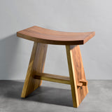 Wooden stool with curved top and straight legs on a gray background