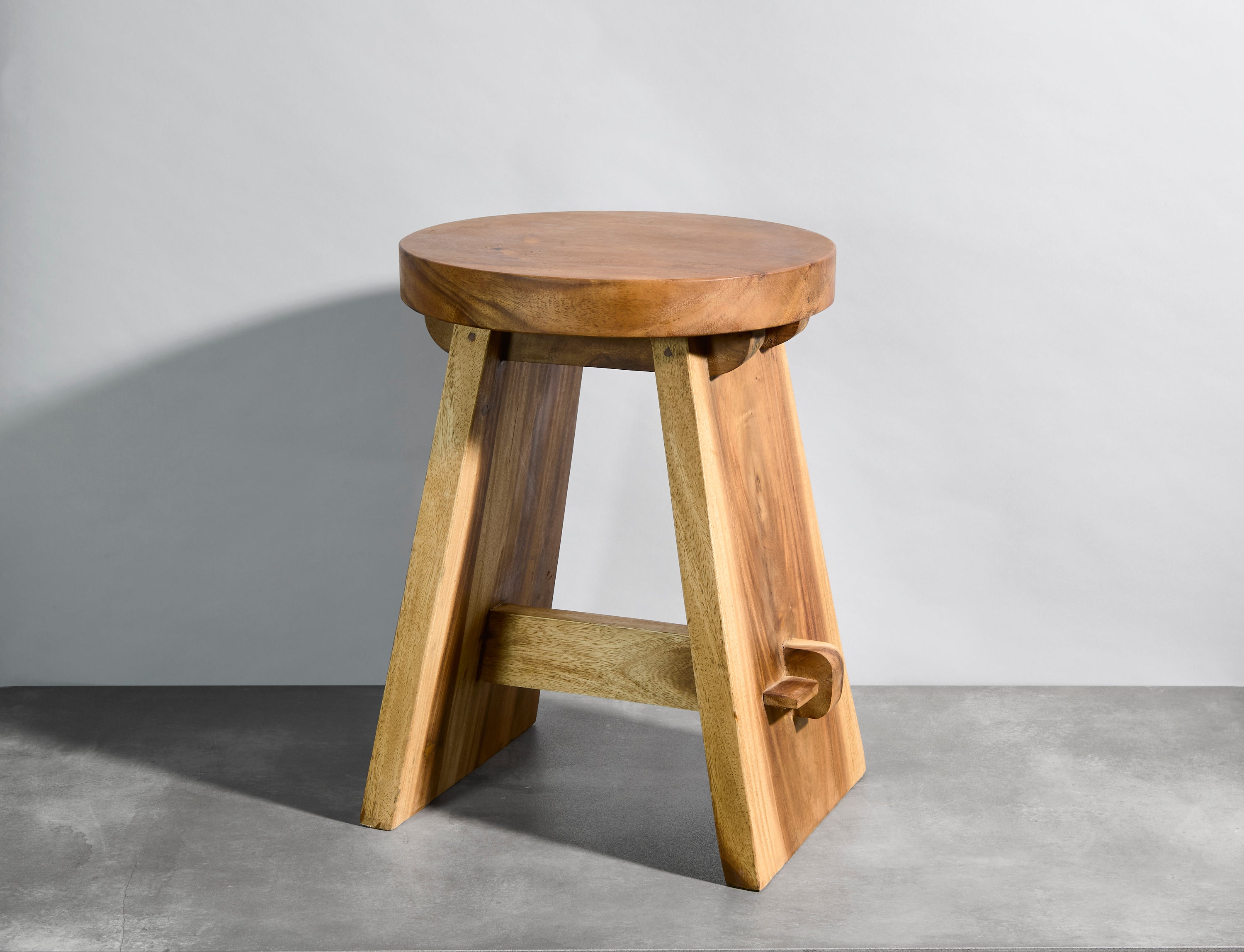 Wooden stool on a gray floor with a plain background