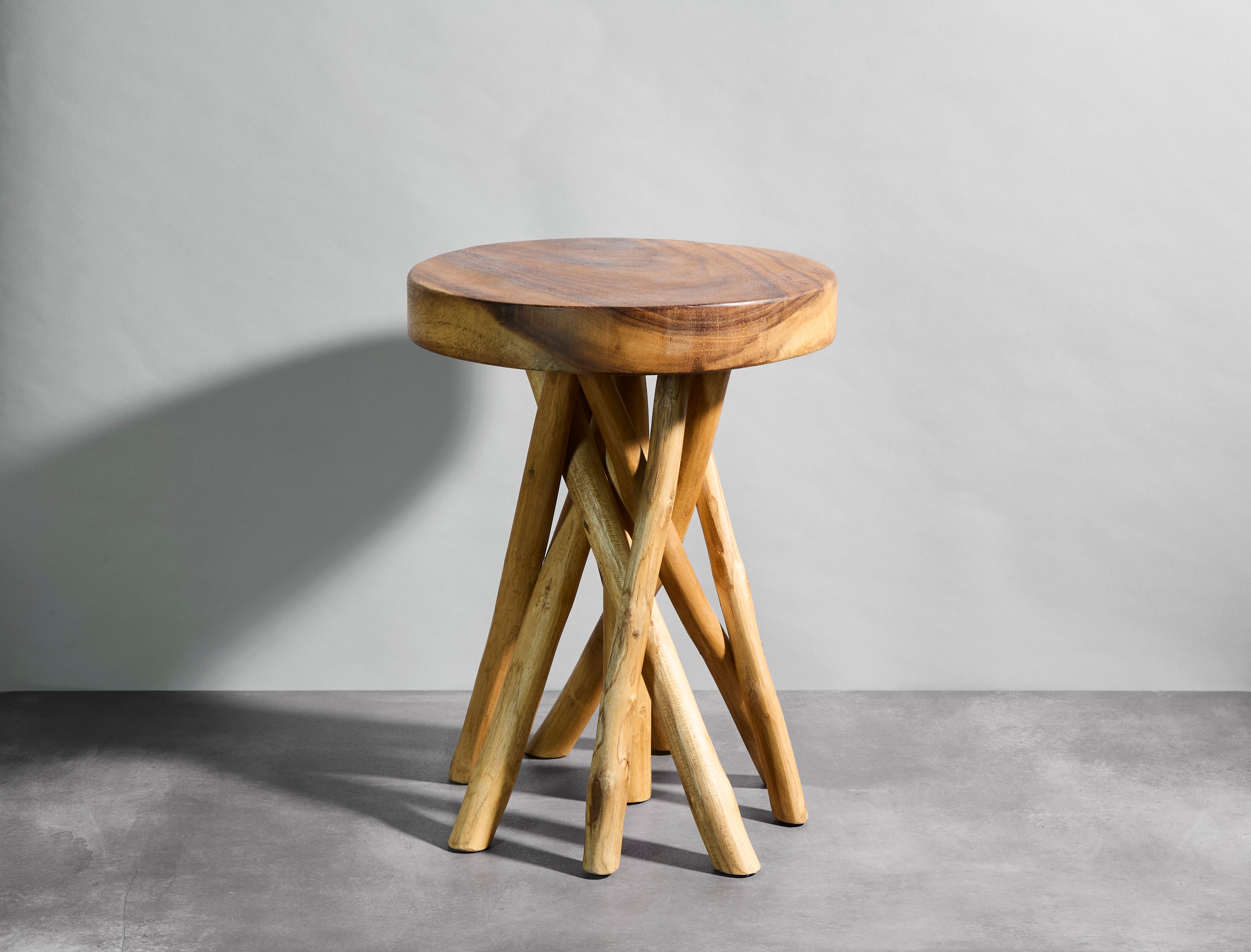 Wooden stool with a round top and twisted legs on a gray background