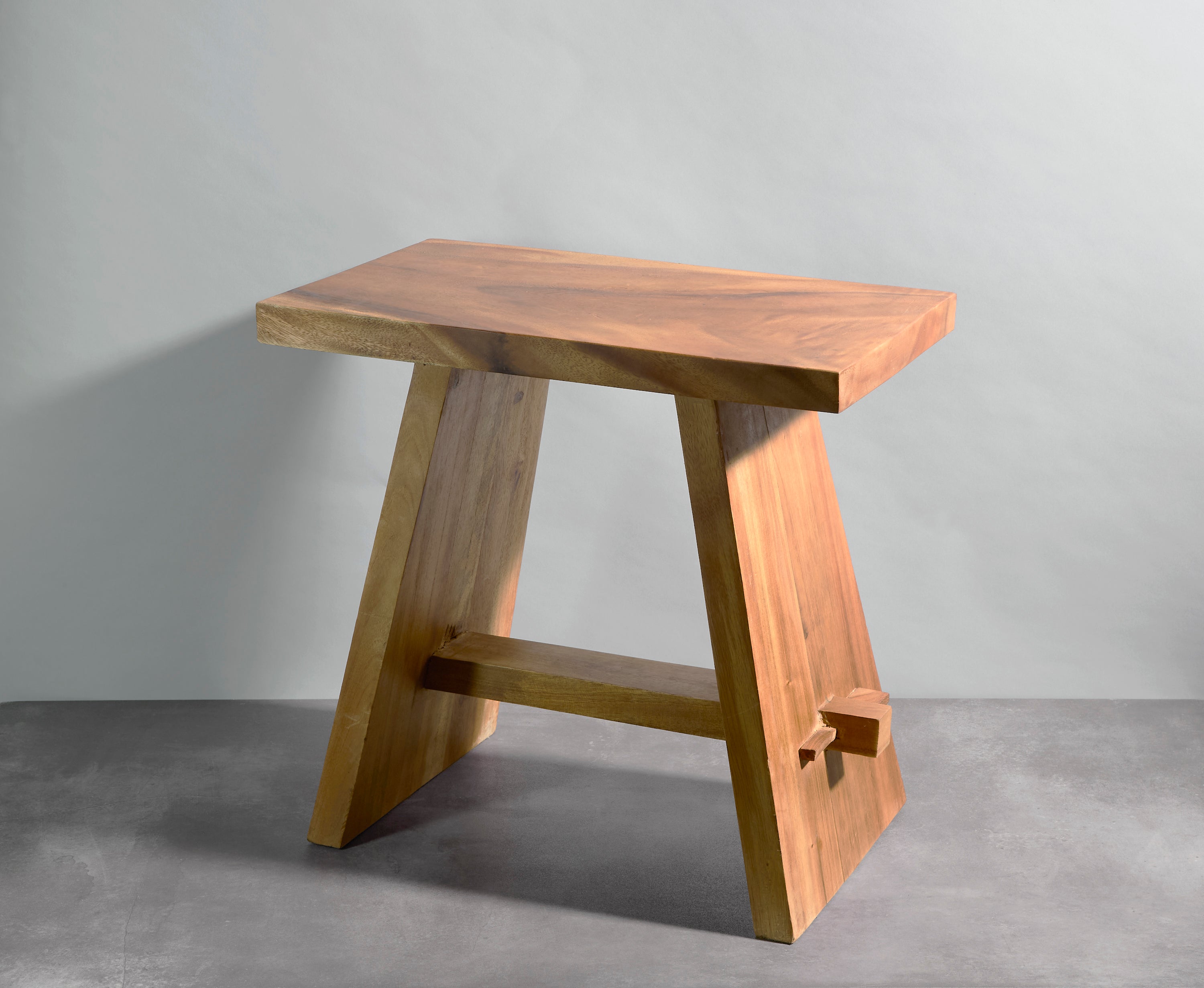 Wooden stool with a natural finish on a gray background