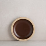 Brown ceramic plate with beige rim on a light gray background