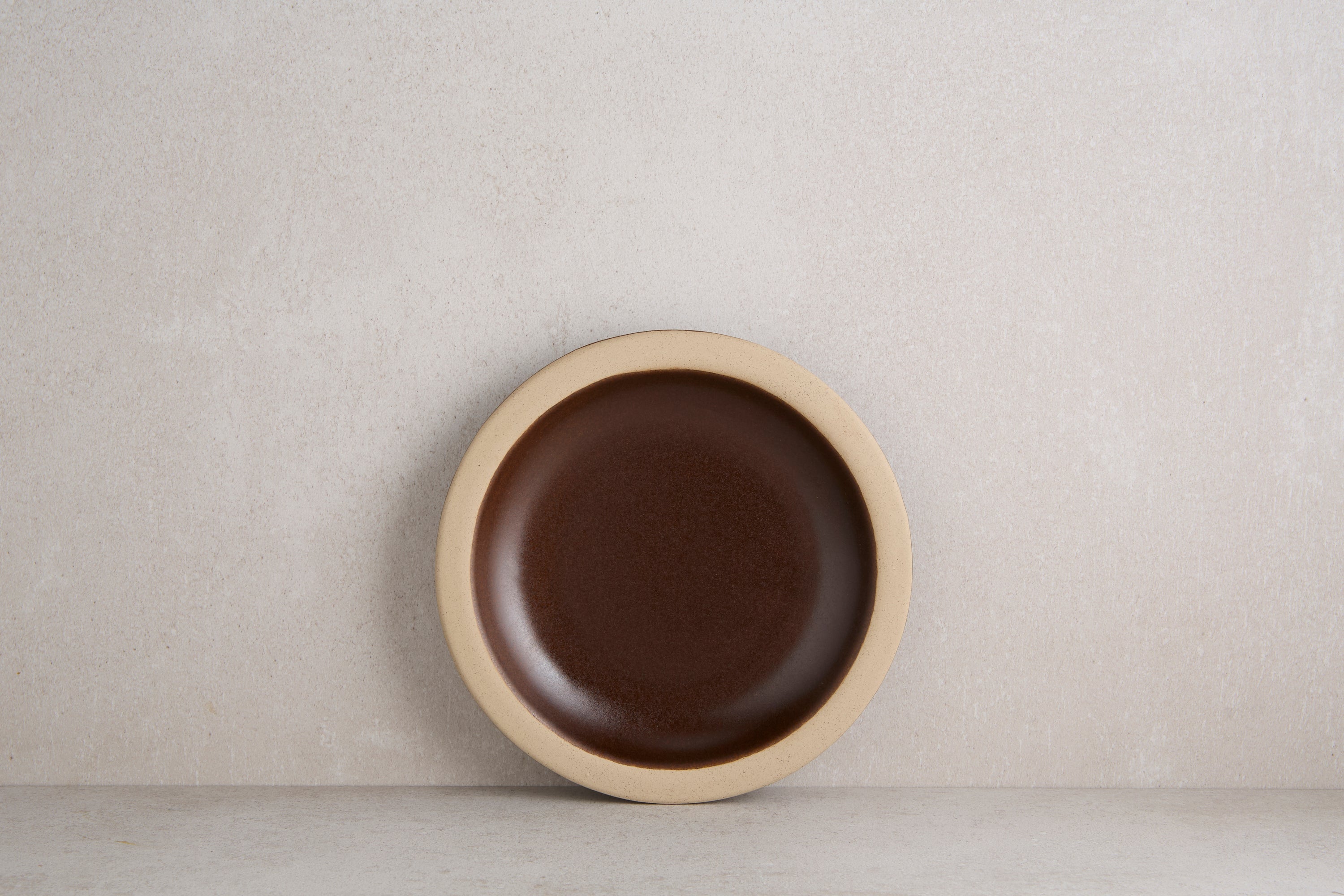 Brown ceramic plate with beige rim on a light gray background