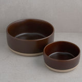 Two brown ceramic bowls on a light gray surface with a neutral background