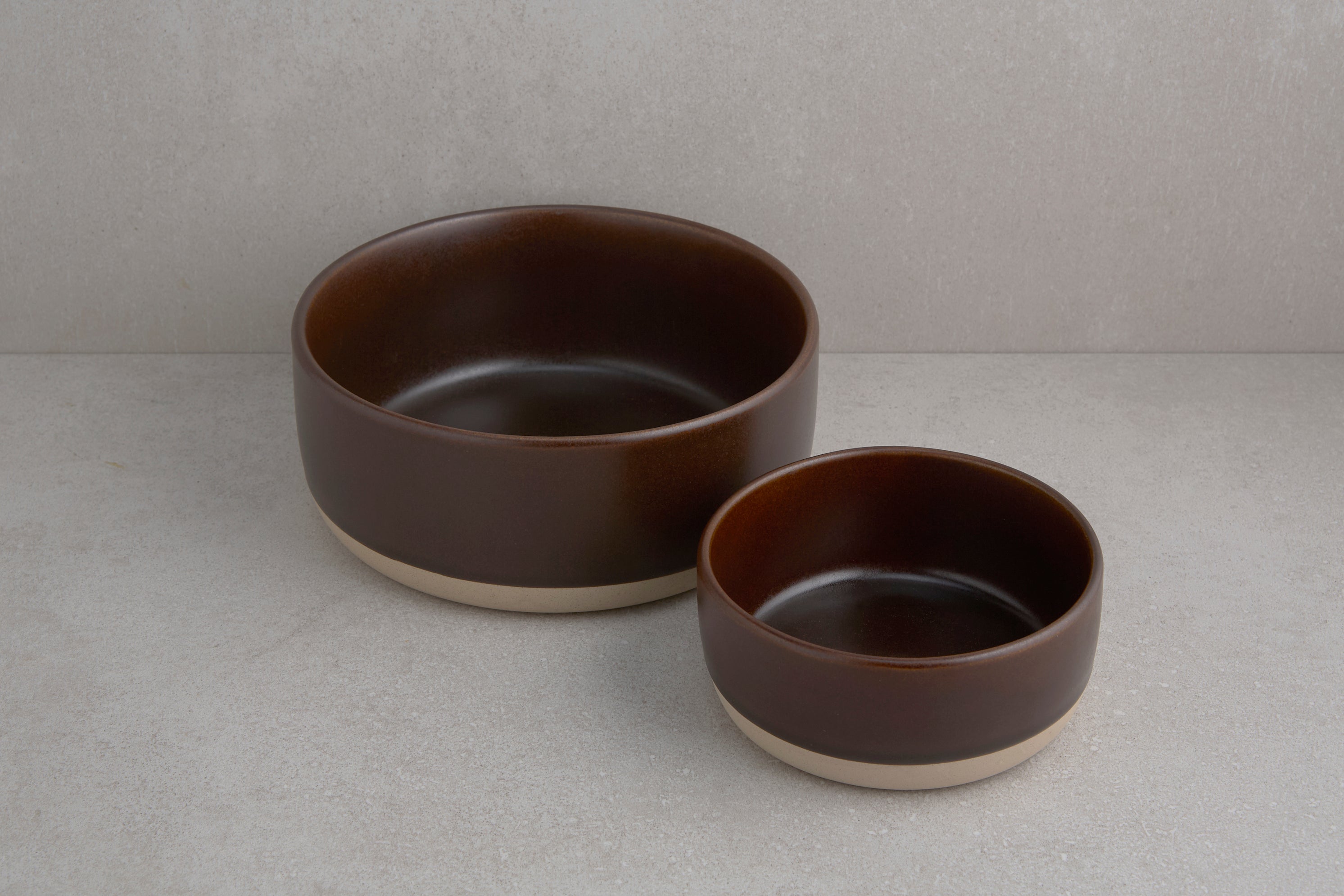 Two brown ceramic bowls on a light gray surface with a neutral background