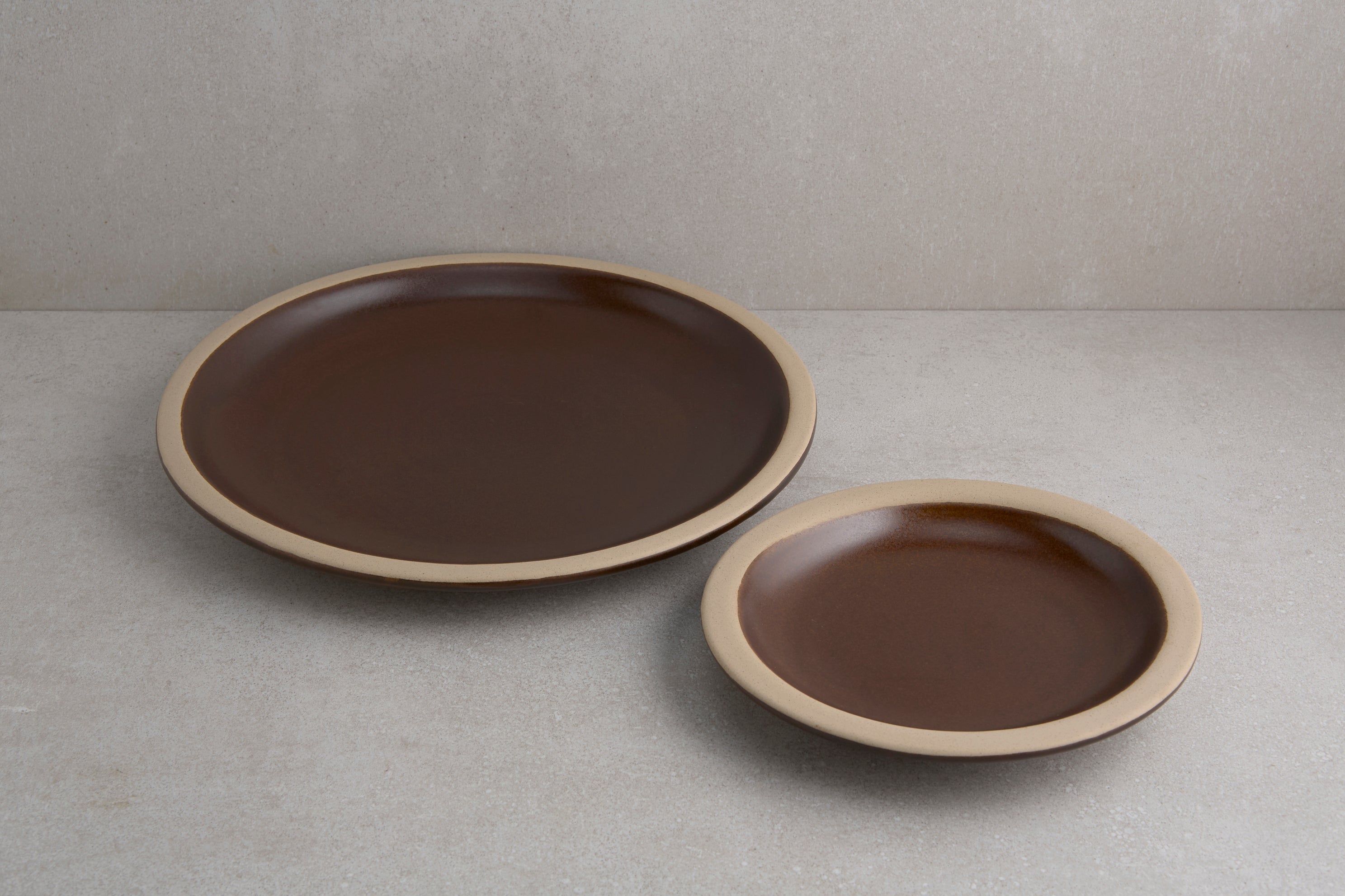 Two brown ceramic plates on a gray surface