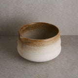 Ceramic bowl with brown and white gradient on a gray background. 