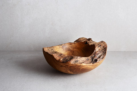 A wooden catchall bowl with a rustic design, displayed on a grey surface.